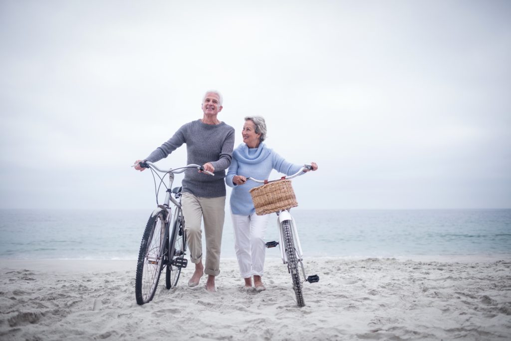 Pärchen steht mit Fahrrädern am Strand