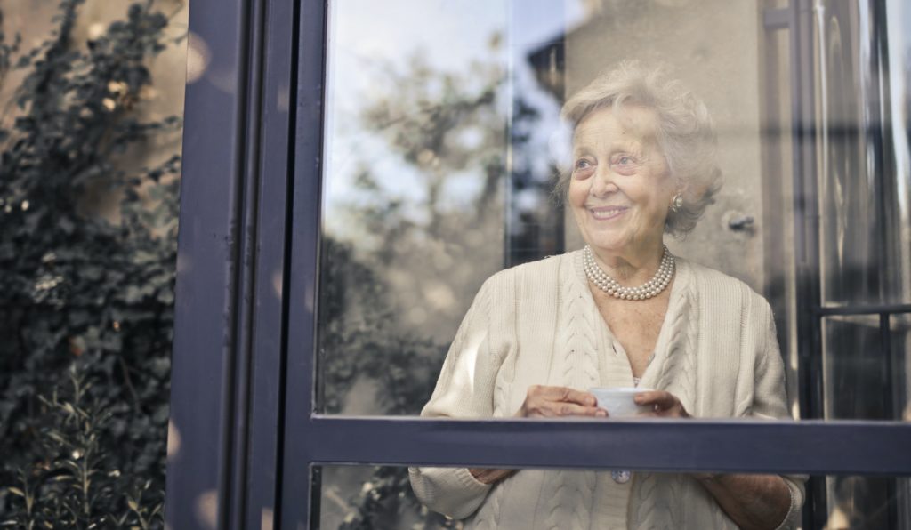 Seniorin steht am Fenster