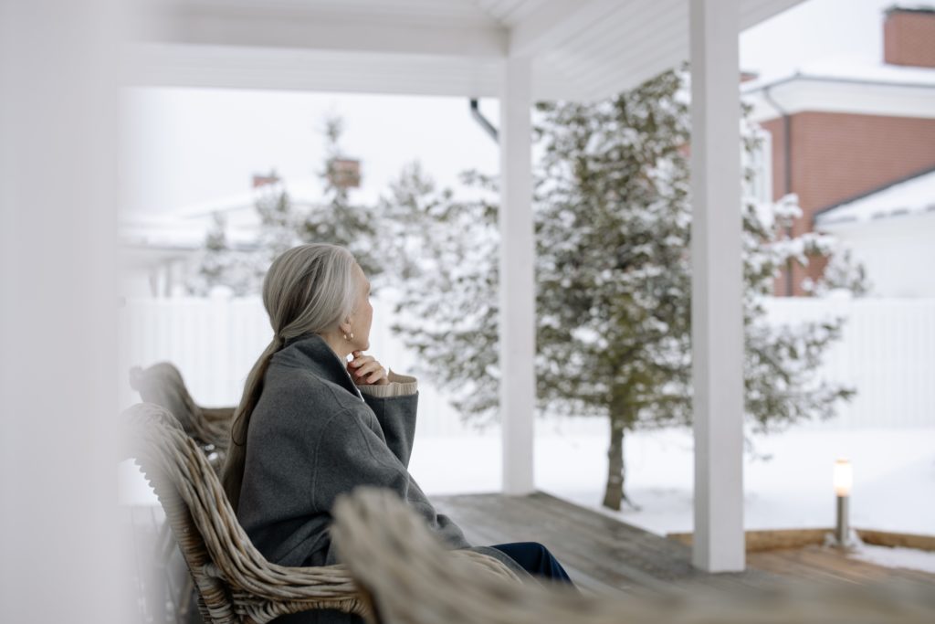 Seniorin auf der Terasse im Schnee
