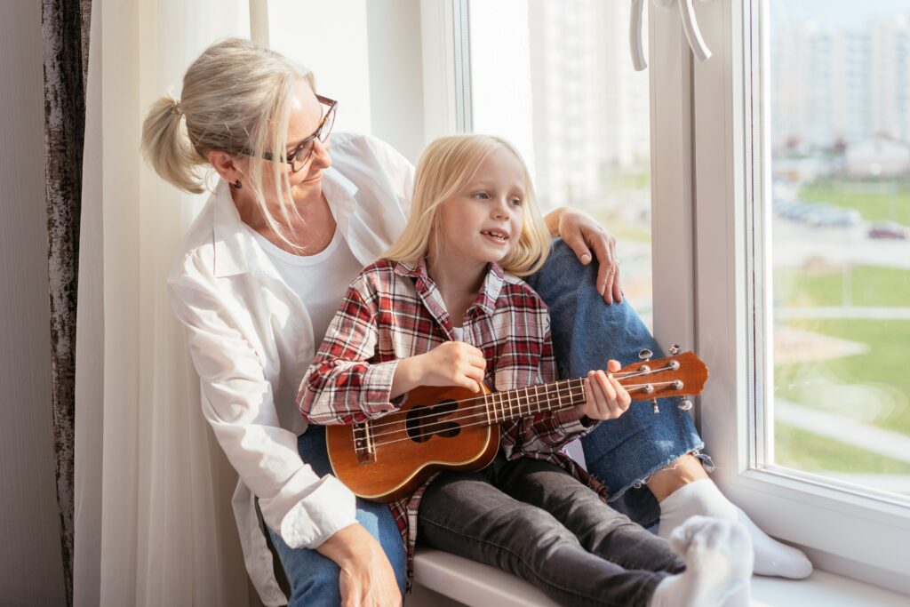 Oma und Enkelin sitzen am Fenster mit Gitarre