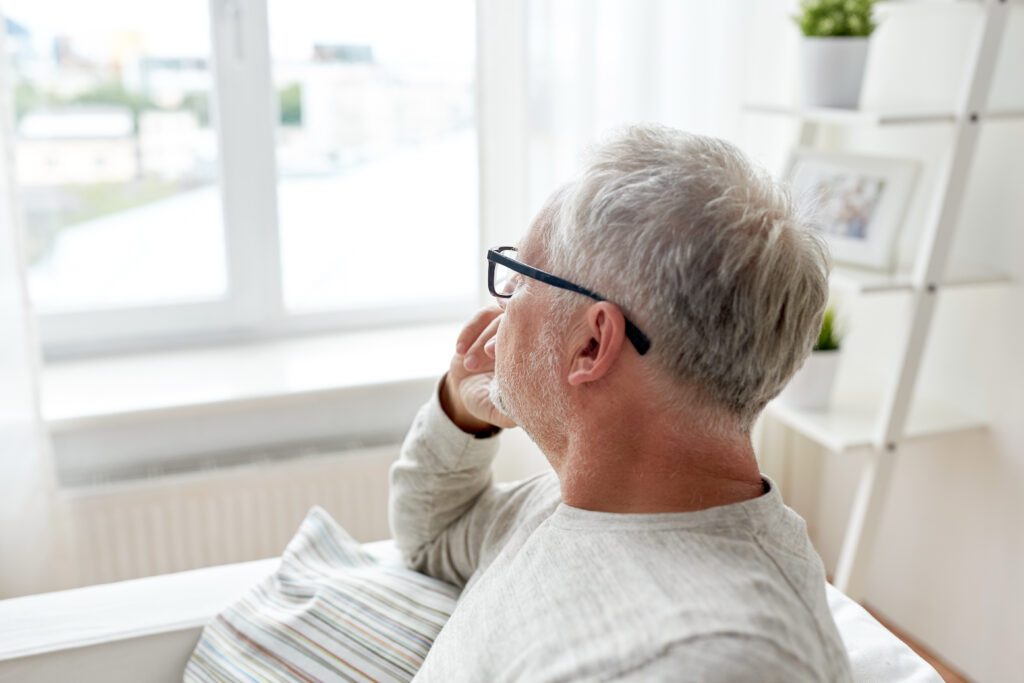 Senior schaut nachdenklich aus dem Fenster