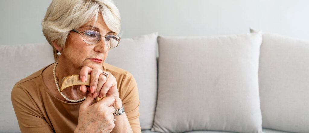 Seniorin sitzt traurig auf dem Sofa