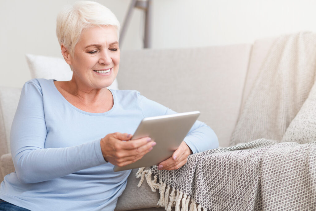 Seniorin mit iPad im Wohnzimmer