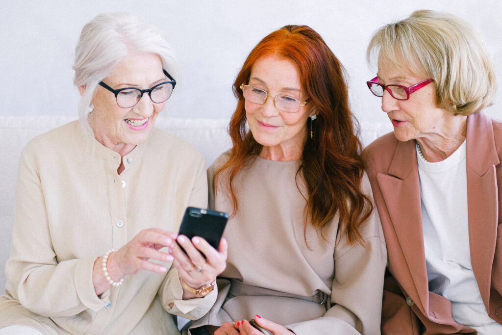 Senioren Freundinnen auf Sofa lachend am Handy
