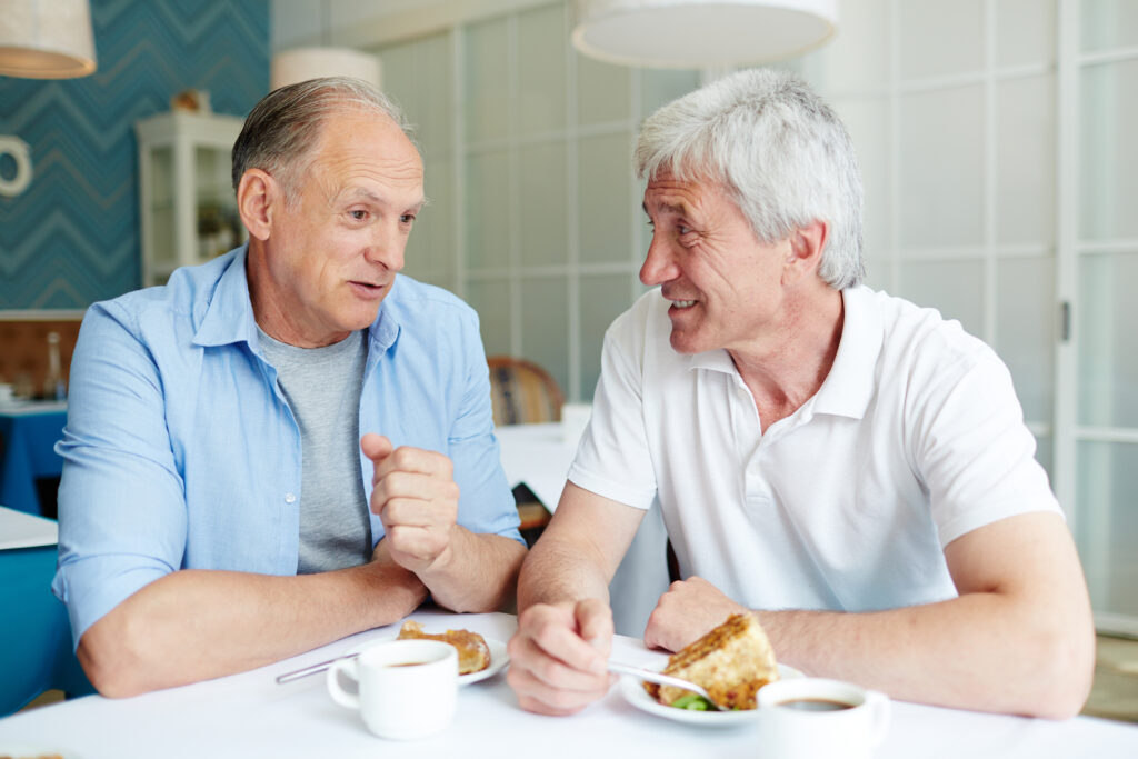 Senioren Freunde sitzen gemeinsam am Tisch und essen
